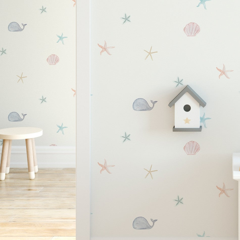 Descubre nuestro Papel Pintado Fondo Marino con dibujos marinos: ballena, conchas y estrella de mar para decorar la habitación infantil. Un diseño delicado y muy suave para una decoración náutica llena de encanto.