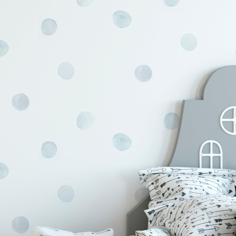 Detalle de habitación de niño decorada con papel pintado lunares azul claro neutro
